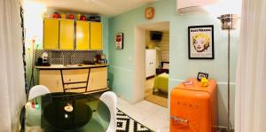 een keuken met een glazen tafel en een oranje koelkast bij La Maison Pop Appartement meublé indépendant avec jardin in Romans-sur-Isère