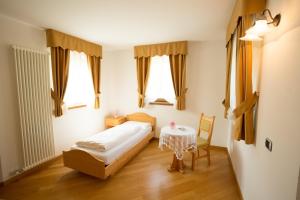 a bedroom with a bed and a table and windows at Hotel Fior Di Bosco in Giovo