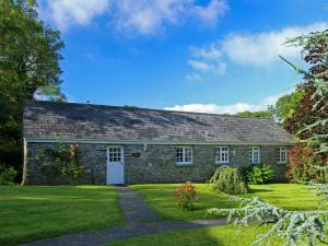 una antigua casa de piedra con un patio de césped en Drovers, en Lanteglos