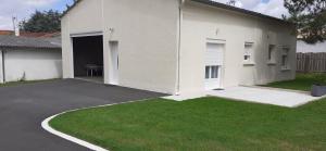 una casa blanca con garaje y patio de césped en Le logis de Chantal en pays royannais en Arvert