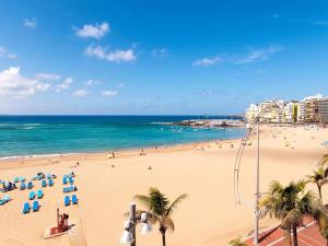 uma praia com cadeiras e palmeiras e o oceano em Coqueto apartamento a 50 metros de la playa em Las Palmas de Gran Canaria
