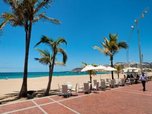 una playa con sillas, palmeras y el océano en Precioso apartamento a 150 metros de la Playa, en Las Palmas de Gran Canaria