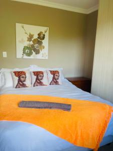 a bed with an orange blanket with two women on it at Toriso Hotels Group in Nelspruit