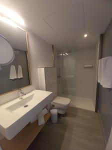 een badkamer met een wastafel, een toilet en een spiegel bij Apartamentos Marivista in Playa del Inglés
