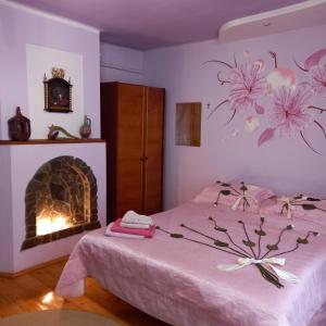um quarto com lareira e uma cama com flores cor-de-rosa na parede em Лаванда em Yaremche