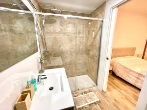 een badkamer met een wastafel, een douche en een bed bij Hospedaje24 - 1 in Manresa