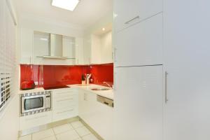 a kitchen with white cabinets and red walls at Sea La Villa Port Douglas in Port Douglas