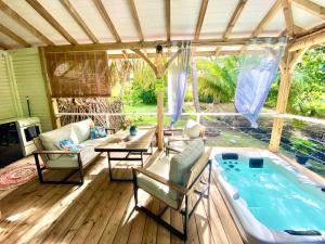 un patio con vasca idromassaggio, tavolo e sedie. di Villa Gaïa - Bungalow Ti-Spa et son jacuzzi privé dans un jardin tropical, séjour en amoureux ou en famille a Le Diamant