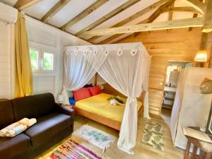 una camera da letto con un letto a baldacchino di Villa Gaïa - Bungalow Ti-Spa et son jacuzzi privé dans un jardin tropical, séjour en amoureux ou en famille a Le Diamant