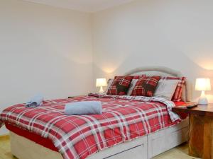 Schlafzimmer mit einem Bett mit einer roten und weißen karierten Decke in der Unterkunft Smiddy Bothy in Edzell