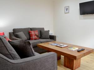 a living room with a couch and a coffee table at Smiddy Bothy in Edzell