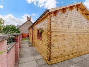 a wooden shed with a roof on a patio at Smiddy Bothy in Edzell