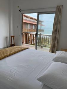 a bedroom with a large white bed and a large window at Samana Hostal, Puerto Engabao in Engabao