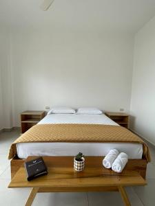Una cama con toallas y un libro sobre una mesa de madera. en Samana Hostal, Puerto Engabao, en Engabao