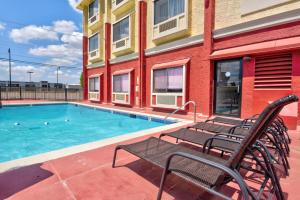 Ramada by Wyndham Oklahoma City Airport North في مدينة اوكلاهوما: مسبح مع كرسيين بجانب مبنى