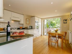 a kitchen with white cabinets and a table with wine glasses at Rose Cottage in Poynings