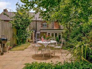 a patio with a table and chairs in a garden at Rose Cottage in Poynings