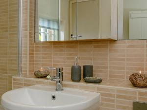 een badkamer met een wastafel, een spiegel en kaarsen bij Rose Cottage in Poynings