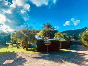 um sinal de rua num parque com palmeiras em Villa Gaïa - Bungalow Ti-Spa et son jacuzzi privé dans un jardin tropical, séjour en amoureux ou en famille em Le Diamant