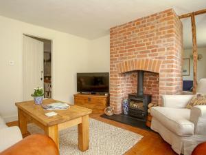a living room with a brick fireplace and a table at Pilgrim Cottage in Hollingbourne