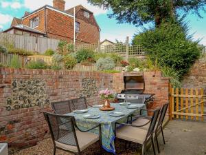 a patio with a table and chairs and a brick wall at Pilgrim Cottage in Hollingbourne