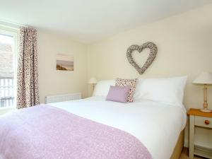 a bedroom with a white bed with a heart on the wall at Pilgrim Cottage in Hollingbourne