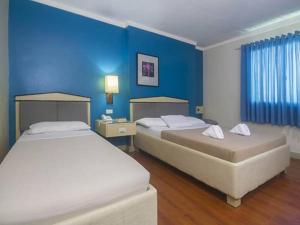 two beds in a room with blue walls at New Dawn Pensionne House in Cagayan de Oro