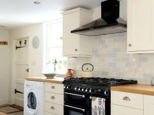 a kitchen with a stove and a washing machine at Pilgrim Cottage in Hollingbourne