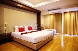 1 dormitorio con 1 cama blanca grande con almohadas rojas en The Ninth Place Serviced Residence, en Bangna