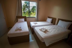 two beds in a room with a window at Pousada dos Corais in Mundaú