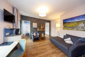 ein Wohnzimmer mit Couch und Fernseher in der Unterkunft Hotel Halfenstube & Villa Spa 1894 in Senheim