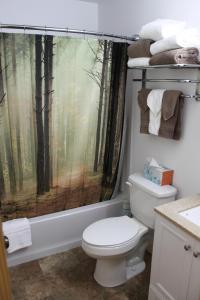 a bathroom with a toilet with a forest shower curtain at Susitna River Lodging, Backwoods Cabins in Talkeetna