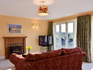 a living room with a red couch and a television at Grange Cottage in Winston