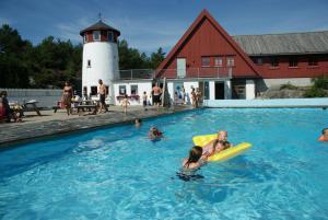 a group of people in a swimming pool with a lighthouse at Skottevik Feriesenter in Skottevik