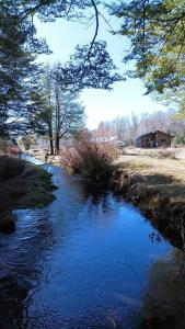 a stream of water with a house in the background at Cabaña Los Chilcos in Curacautín