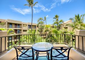 a balcony with a glass table and two chairs at Paki Maui by HI in Lahaina