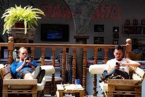 Due uomini seduti sulle sedie che guardano i loro cellulari di Pariwana Hostel Cusco a Cuzco