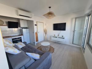 ein Wohnzimmer mit einem Sofa und einer Küche in der Unterkunft Appartement lumineux avec vue sur mer in La Grande-Motte