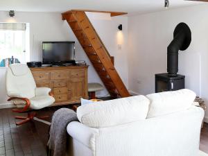 a living room with a white couch and a wood stove at Stable Cottage in Icklesham