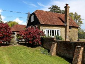 an old brick house with a brick wall at Stable Cottage in Icklesham