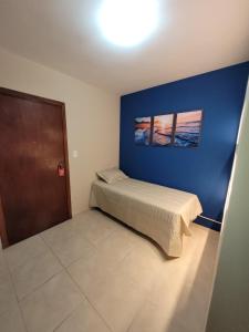 - une chambre avec un lit et un mur bleu dans l'établissement Flat Completo Novo a 400m da praia com piscina, à São Vicente