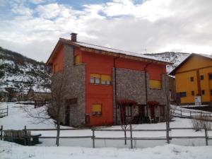 a red and yellow building in the snow at Hostal Casa La Picota in Cofiñal