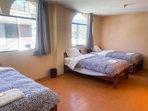 a room with three beds and two windows at Homestay Pachamama in Cabanaconde