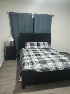 a bed with a plaid blanket and pillows on it at Casa en puntaleona Condomio Bambu in Quebrada Ganado