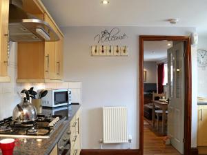 a kitchen with a stove and a microwave at 2 West Cottage in Blakeney