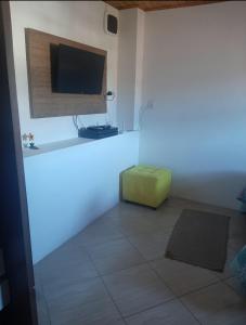 een woonkamer met een televisie en een groene poef bij Casa Eudileia in Campos do Jordão