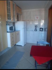 een keuken met een witte koelkast en een rode tafel bij Casa Eudileia in Campos do Jordão