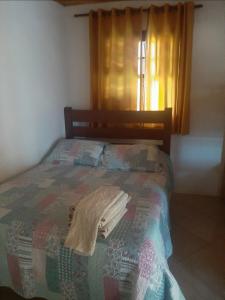 een slaapkamer met een bed met een deken en een raam bij Casa Eudileia in Campos do Jordão