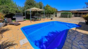 a blue swimming pool with a table and an umbrella at Castlereagh Lodge Motel in Coonamble