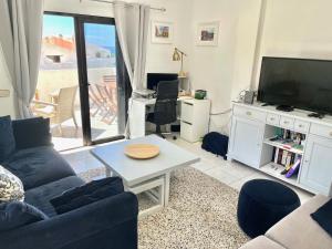 a living room with a couch and a tv and a table at Sea View Penthouse with Large Terrace in Los Cristianos